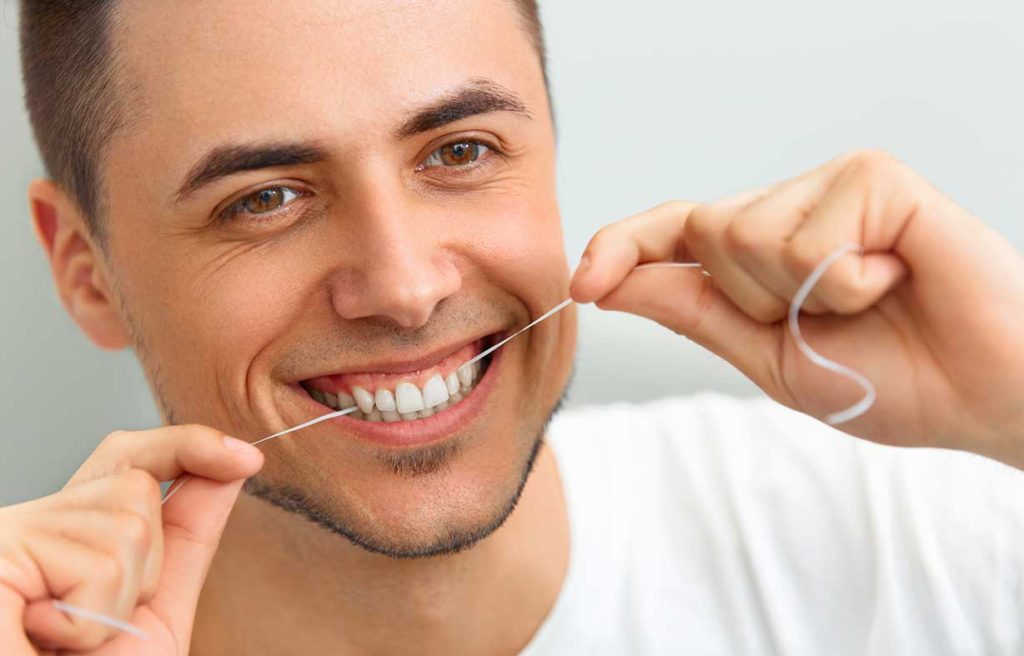 A man flossing his teeth. Ivy Lane Dentistry offers leading periodontal care for all ages in Terrell Hills, TX and San Antonio, TX