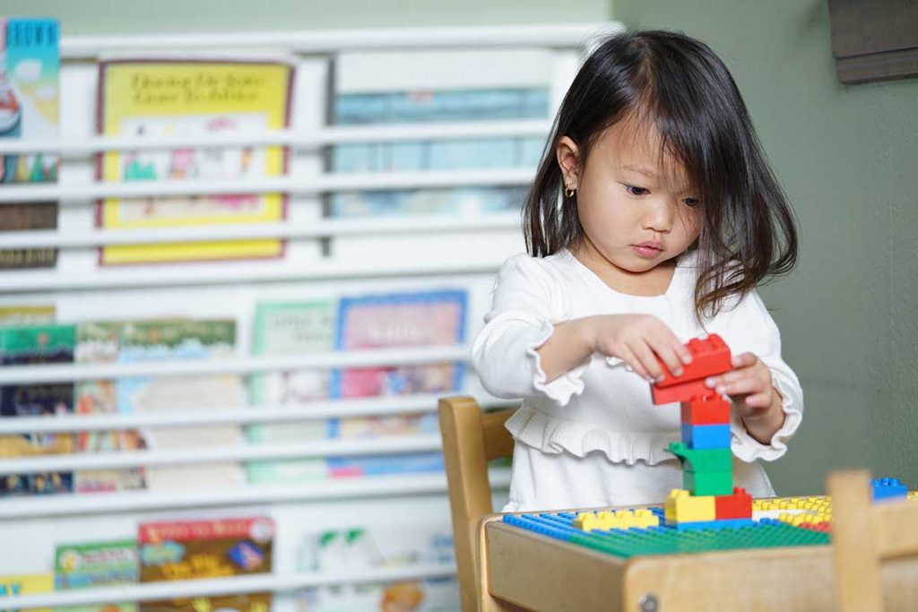 a cute little girl arranging the blocks. Ivy Lane Dentistry offers early care and monitoring of young teeth to ensure proper dental care for the future in San Antonio, TX. 