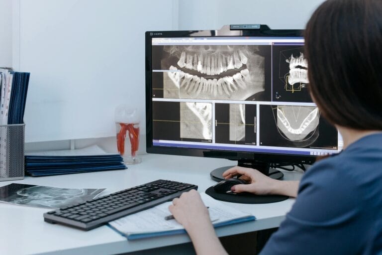 Dentist examining dental X-rays on a computer screen in a clinic.