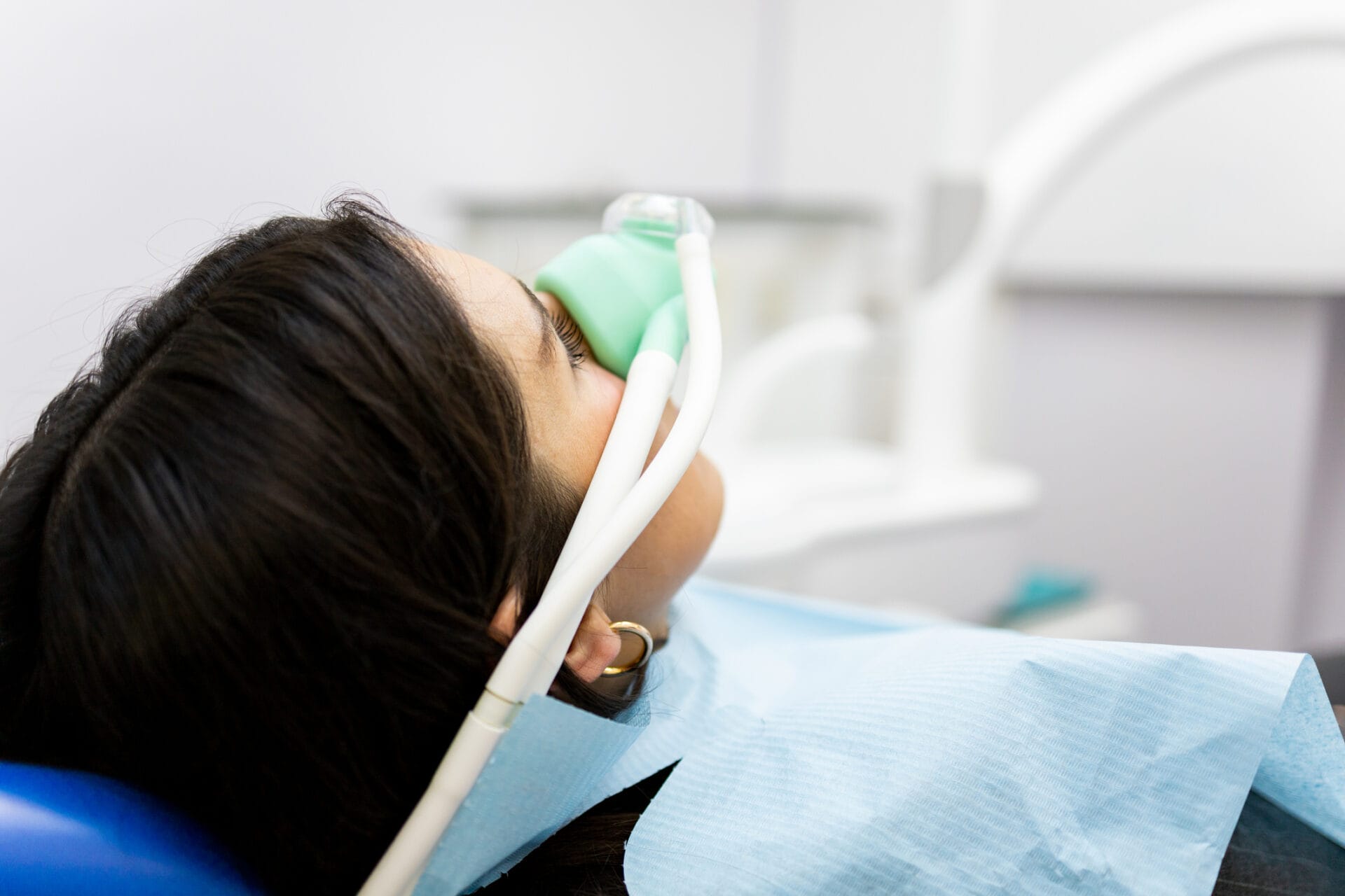 A woman sits in a dentist's clinic wearing a nasal mask for sedation dentistry